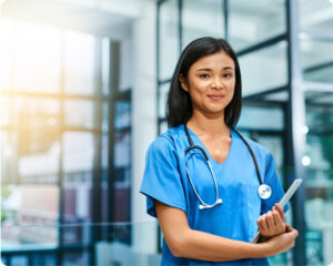 Young nurse wearing stethoscope and carrying tablet in hospital setting