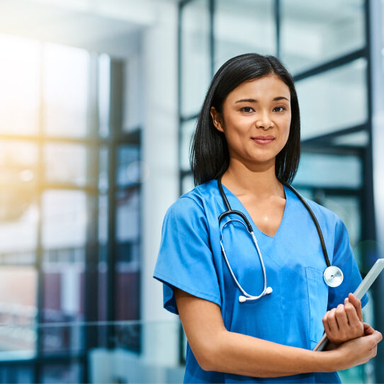 Young nurse wearing stethoscope and carrying tablet in hospital setting